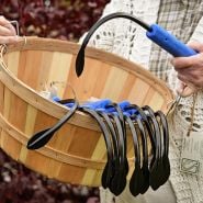 Hands holding a basket full of CobraHead Hand Hoe Tools with one tool being held in left hand.