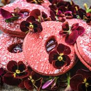 A bunch of Arkwright Ruby Viola Pansy with some red velvet cakes on a wood board.             
