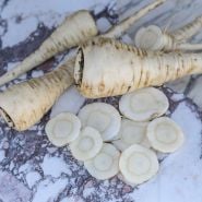Half Long Guernsey Parsnip with slices on marble background.