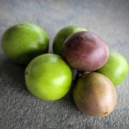 Whole Possum Purple Passion Fruit in various stages of ripeness arranged on stone background.