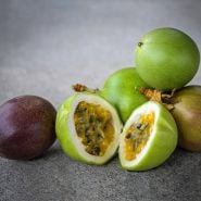 Cut and whole Possum Purple Passion Fruit on a stone background.