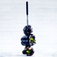 Three stacked Purple Beauty Peppers are held in place by a knife on a light background.