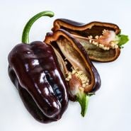 A close-up of cut and whole Sweet Chocolate Sweet Peppers on a white background.