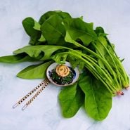 Jiromaru Spinach leaves with some cooked in bowl with chopsticks on light green background.