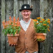 The Bakersville town sheriff holding a couple of blooming plants at the Baker Creek Spring Planting Festival.