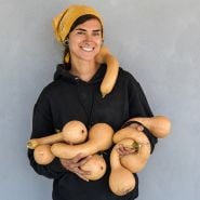 A Baker Creek employee holding newly harvested Canada Crookneck Winter Squash.