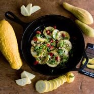 Early Prolific Straightneck Summer Squash grilled in a cast iron skillet on a wood background.