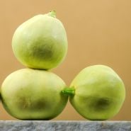 A trio of Desi Summer Squash on white marble with a tan background.