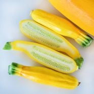 Halved and whole Golden Zucchini Summer Squash on a white background.