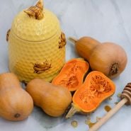 Cut and whole Honeynut Butternut Winter Squash on light background.