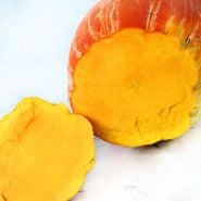 Gete Okosomin or Kentucky Winter Squash cut open to show the orange flesh on white marble countertop.