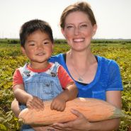 A smiling mother and son holding Candy Roaster - North Georgia Winter Squash in the field.