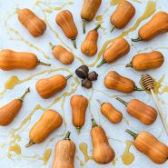 Honeynut Butternut Winter Squash arranged in circle with honey and some wooden carved acorns.