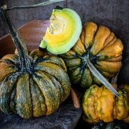 Cut and whole Guicoy Winter Squash with broken pots against a vintage wood background.