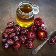King Size Red Strawflower tea with floers at the base of the tea and spoon on a copper background.