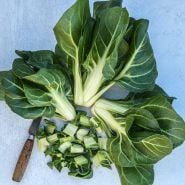 Three heads of Barese Swiss Chard with hchopped leaves and old knife on light baackground.