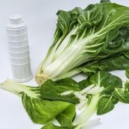A head of Barese Swiss Chard with leaves and a Leaning Tower of Pisa ceramic cheese container.