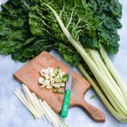 Fordhook Giant Swiss Chard with chopped stems on a cutting board on a light blue background.