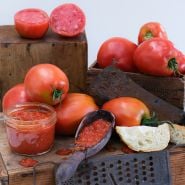 Amish Paste Tomatoes processed as paste in a jar and spoon arrange on on wooden boxes.