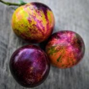 A close-up of a Trio of Black Strawberry Tomatoes on a wooden background.
