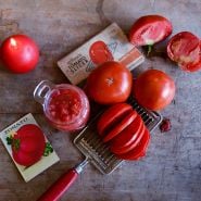 Whole, sliced and cut Bonnie Best Tomatoes on a cutting board with some in a jar.