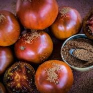 Whole Brown Sugar Tomatoes with slices and brown sugar in a bowl.