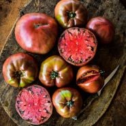 Carbon Tomatoes arranged on a wooden cutting board with a knife.