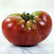 A side view of a single True Beefsteak or Fejee Improved Tomato on white marble countertop.