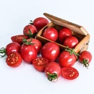 Cut and whole German Lunchbox Tomatoes in and surrounding a wooden box from Germany on white.