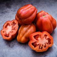 Whole and cut Gezahnte Tomatoes on metal background.