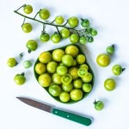 Green Doctors Tomatoes on a white background with a green handled knife.