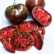 Juicy Paul Robeson Tomato slices with whole tomatoes on linen background.