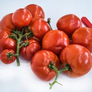 Two generous clusters of Peron Tomatoes still on the vine on a high key background.