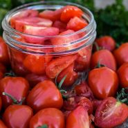 Close-up view of whole and cut Sweetheart Cherry Tomatoes with some in a canning jar.