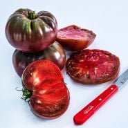 Cut and whole True Black Brandywine Tomatoes on a white background.