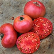 Whole and halved Millionaire Tomatoes on wooden cutting board.