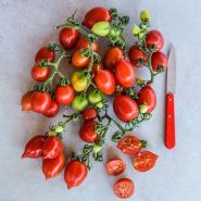 Overhead view of a cluster of Principe Borghese Tomatoes with a knife and some sliced.