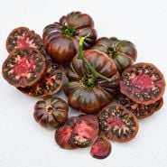 A cluster of sliced and whole Purple Calabash Tomatoes on linen background.