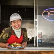 A food vendor smiling and showing her food at the Baker Creek Tulip Festival.