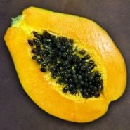 A cut open Waimanalo Papaya on a rustic background.