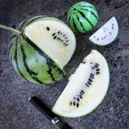 A cut Silver Yamato Watermelon with a Japanese knife and watermelon shaped salt shakers on stone.