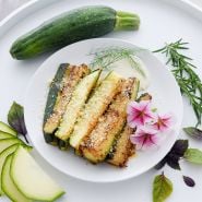 Breaded air fried Black Beauty Zucchini Summer Squash on a plate with garnish.