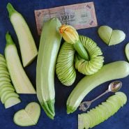 Spiral sliced and regular Long White of Palermo Zucchinis on a wood board with blue background. 