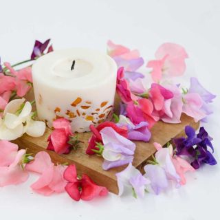 Old Spice Mix Sweet Pea flowers and candle on a wooden cutting board.