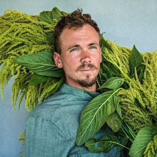 A portrait of the Baker Creek Garden manager with a bountiful harvest of Aurelia's Verde Amaranth.