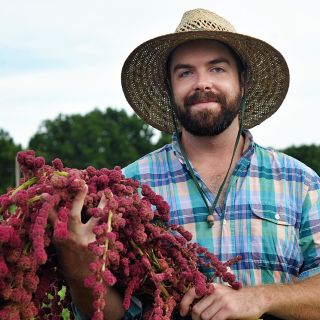 Baker Creek Manager holding a bouquet full of Dreadlocks Amaranth in the trial garden.