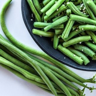 A close-up of a bowl of cut Calima Beans with fresh beans on the side.