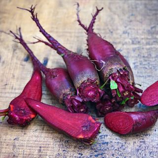Several sliced and whole Renova Beets arranged on a wood background.