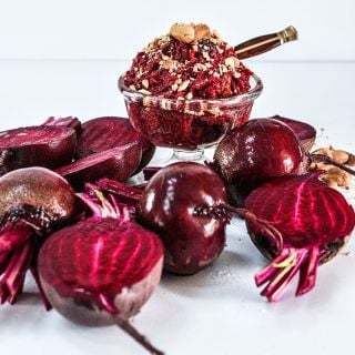 Cut and whole Detroit Dark Red Beets with a desert recipe for Halwa pudding in a glass bowl.