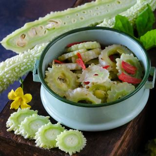 Pickled and raw Long White Reishi Bitter Melons with a bloom and foliage.